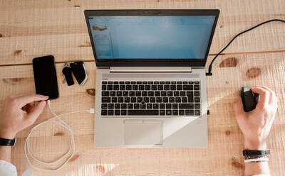 Sky view of a man working from home with his phone and laptop - CAVF69575