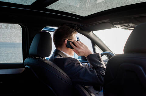 Businessman talking on the phone in his frosty car at home stock photo