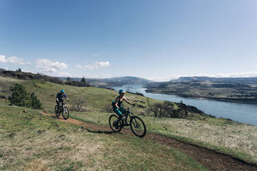 Two young girls bike along a trail overlooking the Columbia River. - CAVF69598