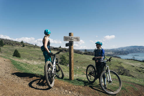 Zwei junge Frauen machen eine Pause beim Mountainbiken im Bundesstaat Washington - CAVF69600