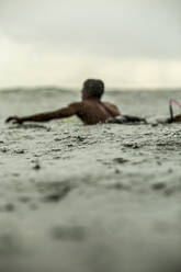 Mann surft im Meer gegen den Himmel während der Regenzeit - CAVF69685