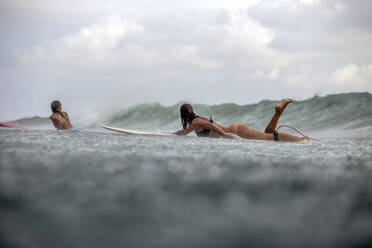 Freunde liegen auf dem Surfbrett beim Surfen im Meer während der Regenzeit - CAVF69688