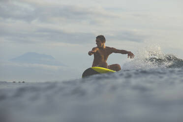 Mann surft im Meer gegen bewölkten Himmel - CAVF69692