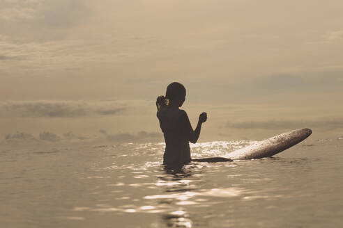 Silhouette Frau mit Surfbrett im Meer stehend - CAVF69694