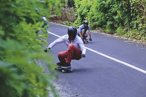 Männliche Freunde beim Skateboarden auf der Straße, lizenzfreies Stockfoto