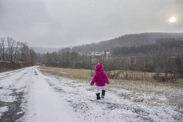 Rückansicht eines Mädchens, das auf einem schneebedeckten Feld läuft - CAVF69733