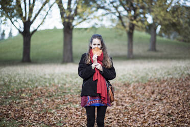 Porträt einer Frau, die ein Ahornblatt hält und auf einem Feld steht - CAVF69744