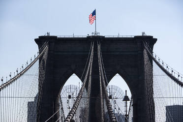 Low angle view of American flag on Brooklyn bridge against clear sky - CAVF69761