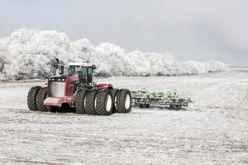 Combine harvester moving on snow covered field - CAVF69783