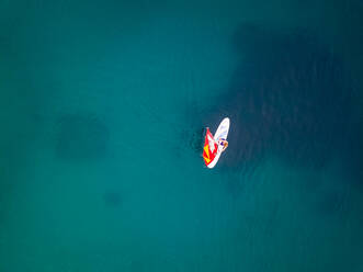 Luftaufnahme eines Mannes beim Kitesurfen auf transparentem Wasser, Kroatien. - AAEF05975