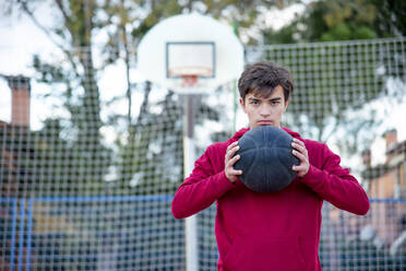 Teenager hält Basketball und schaut in die Kamera - CJMF00193