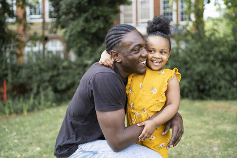 Happy father hugging daughter in a park stock photo