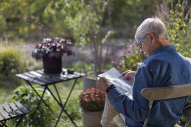 Mann im Garten liest Zeitung - JOHF04659