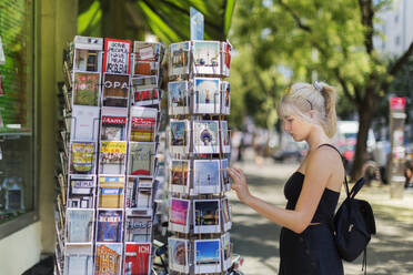 Young woman looking at postcards - JOHF04752
