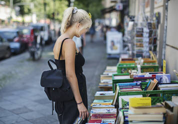 Junge Frau sieht sich Bücher auf einem Verkaufsstand an - JOHF04754