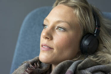 Porträt einer jungen Frau, die mit Kopfhörern Musik hört - MOEF02645