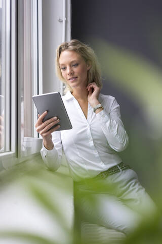 Junge Geschäftsfrau mit Tablet am Fenster, lizenzfreies Stockfoto