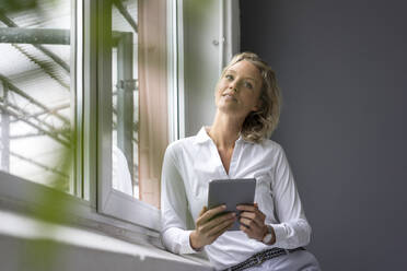 Young businesswoman holding tablet at the window - MOEF02651