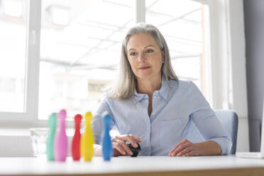 Reife Geschäftsfrau spielt mit Stiften auf dem Schreibtisch im Büro - MOEF02656