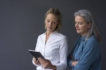 Zwei Geschäftsfrauen betrachten gemeinsam ein Tablet - MOEF02675