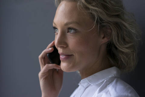 Porträt einer lächelnden jungen Geschäftsfrau am Telefon, lizenzfreies Stockfoto