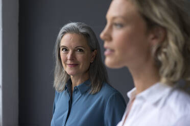 Portrait of confident mature businesswoman with young businesswoman in foreground - MOEF02682