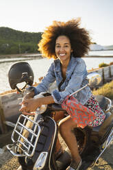 Young woman sitting on motor scooter at sunset, Ibiza - AFVF04358