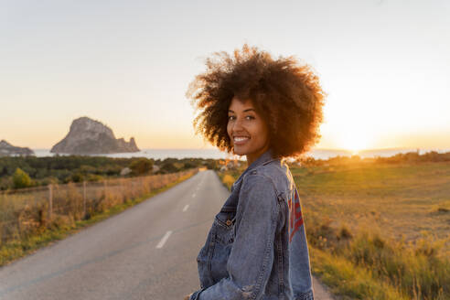 Young woman standing on street and looking at camera at sunset, Ibiza - AFVF04368