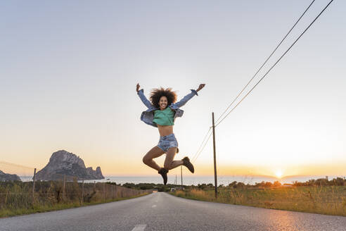 Young woman jumping on street at sunset, Ibiza - AFVF04372