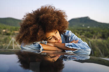 Young woman during road trip, leaning on car roof - AFVF04391