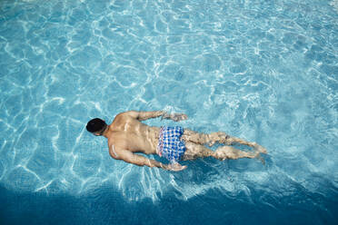Back view of man floating in swimming pool - MIMFF00003