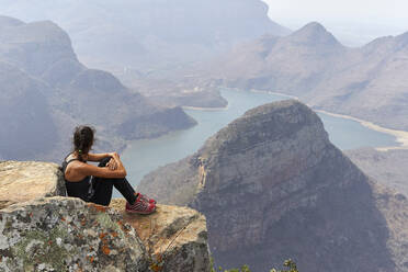 Frau sitzt auf einem Felsen mit schöner Landschaft im Hintergrund, Blyde River Canyon, Südafrika - VEGF01068