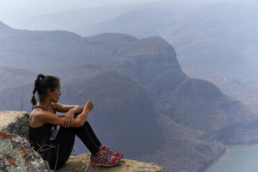 Frau sitzt auf einem Felsen mit schöner Landschaft im Hintergrund, Blyde River Canyon, Südafrika - VEGF01070