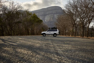 4x4 geparkt auf einer Landstraße mit einem Berg im Hintergrund, Limpopo, Südafrika - VEGF01073