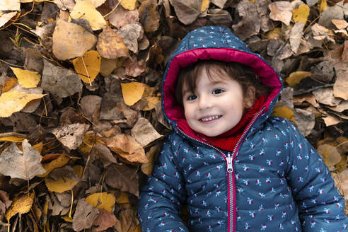 Portrait of happy little girl lying on autumn leaves - GEMF03321