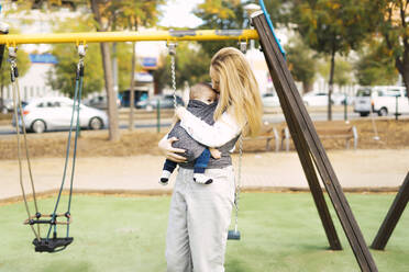 Happy mother with baby boy on a playground - ERRF02247