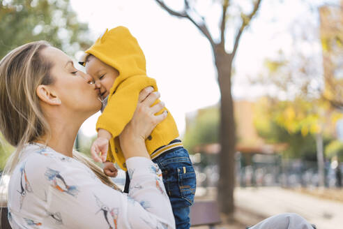 Mutter küsst kleinen Jungen in einem Park - ERRF02253