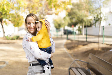 Happy mother carrying baby boy in a park - ERRF02260