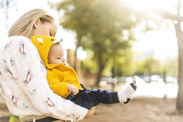 Mother carrying baby boy in a park - ERRF02273