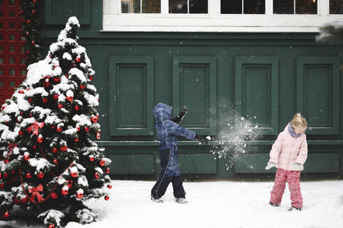 Geschwister bei einer Schneeballschlacht zur Weihnachtszeit - EYAF00739