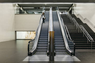 Businesswoman standing on escalator of a subway station - JRFF03892