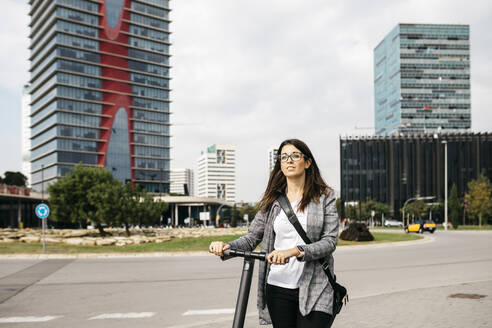 Young businesswoman with e-scooter in the city - JRFF03913