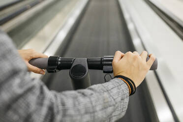 Businesswoman with her electric scooter on moving walkway - JRFF03916