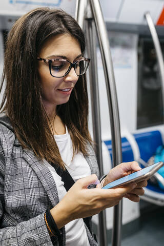 Brünette Frau in der U-Bahn beim Telefonieren auf dem Weg zur Arbeit, lizenzfreies Stockfoto