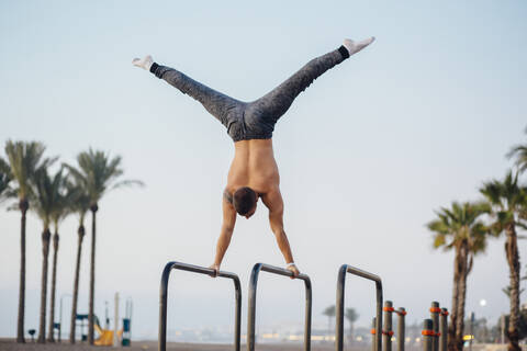 Junger Mann macht Gymnastik in einem Fitnessstudio im Freien, lizenzfreies Stockfoto