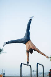 Junger Mann macht Gymnastik in einem Fitnessstudio im Freien - MIMFF00017