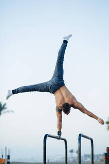 Junger Mann macht Gymnastik in einem Fitnessstudio im Freien - MIMFF00017