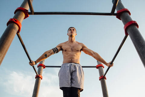 Junger Mann macht Gymnastik in einem Fitnessstudio im Freien, lizenzfreies Stockfoto