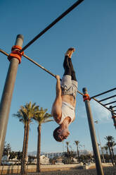 Junger Mann macht Gymnastik in einem Fitnessstudio im Freien - MIMFF00021