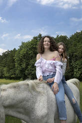 Porträt von zwei besten Freunden, die zusammen auf einem Pferd reiten - PSTF00509